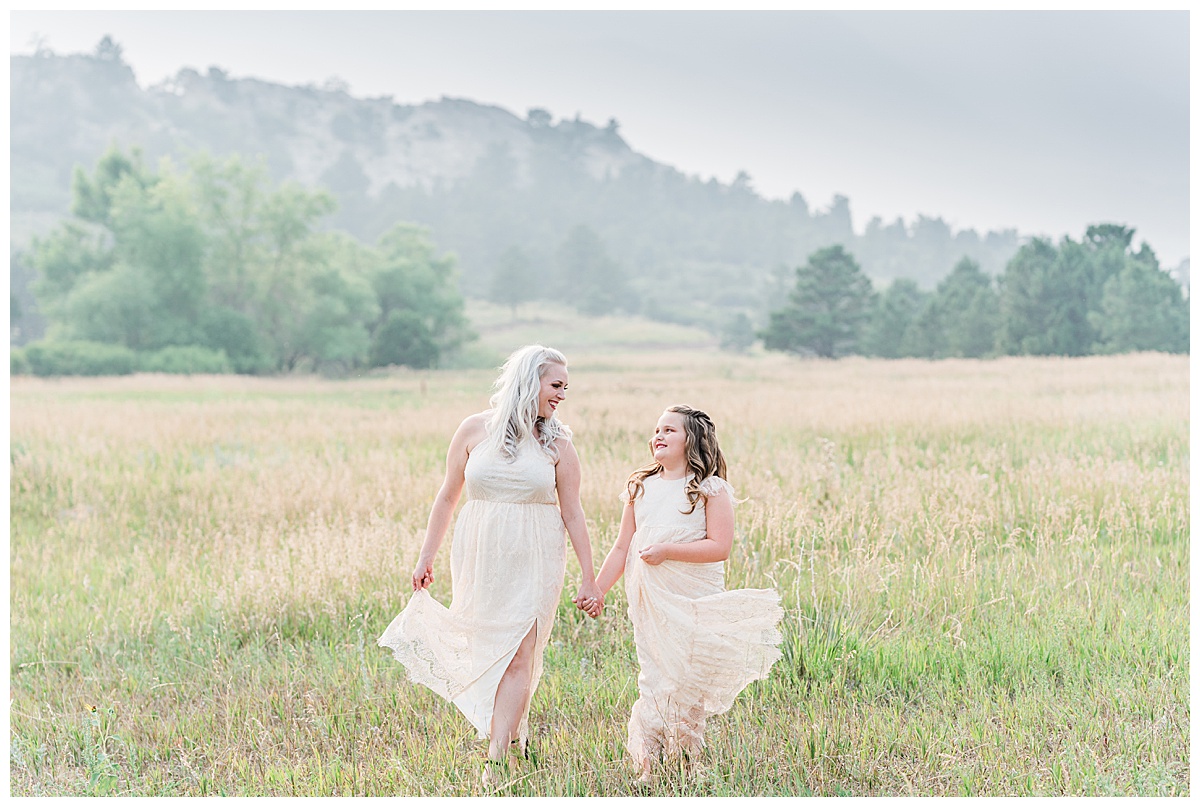 mom and daughter walk through meadow