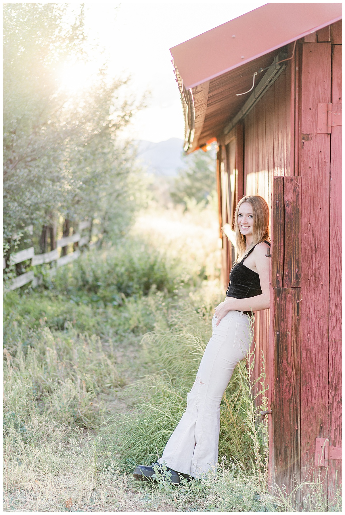 girl leaning on red barn for senior photos