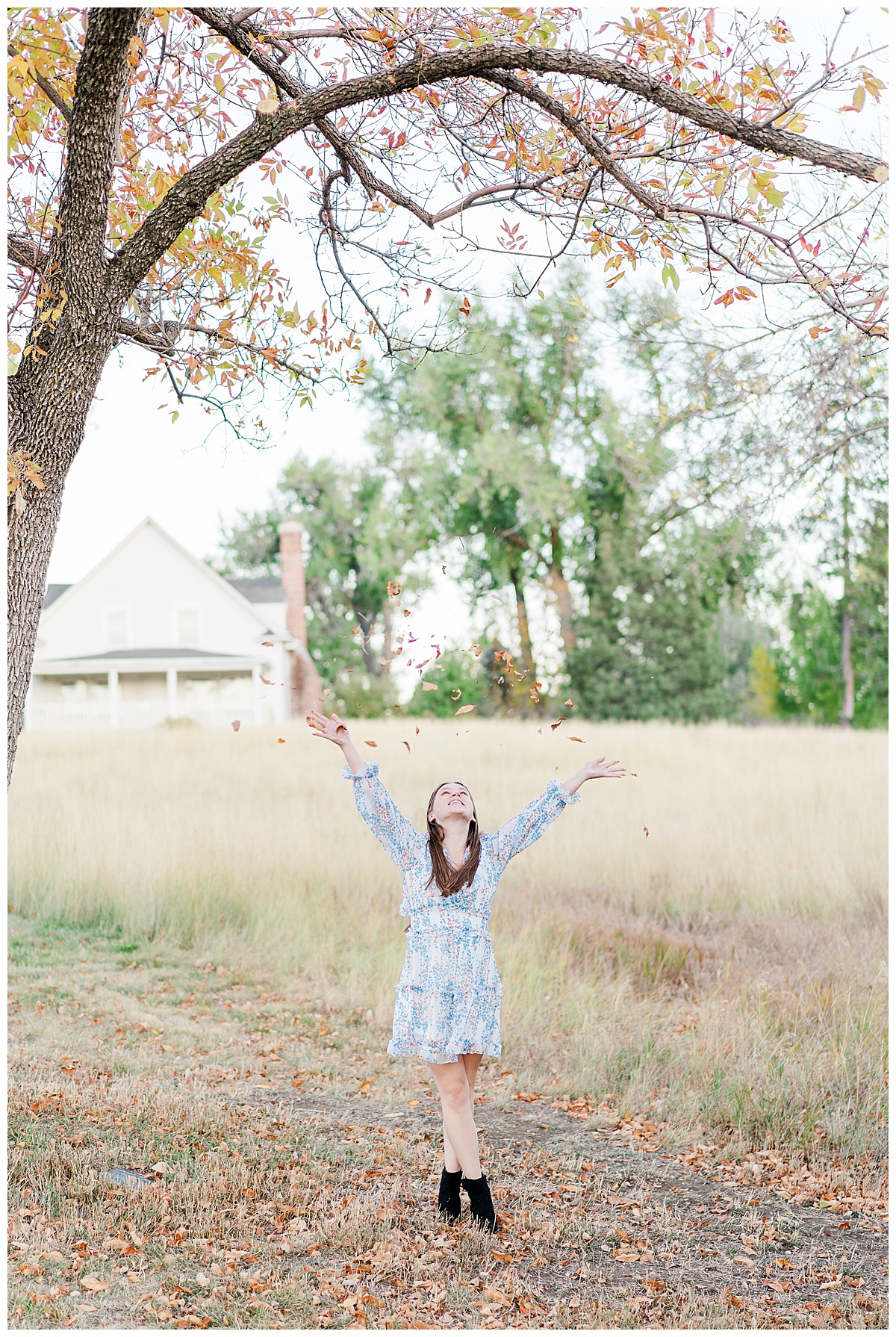 senior girl throwing fall leaves in the air