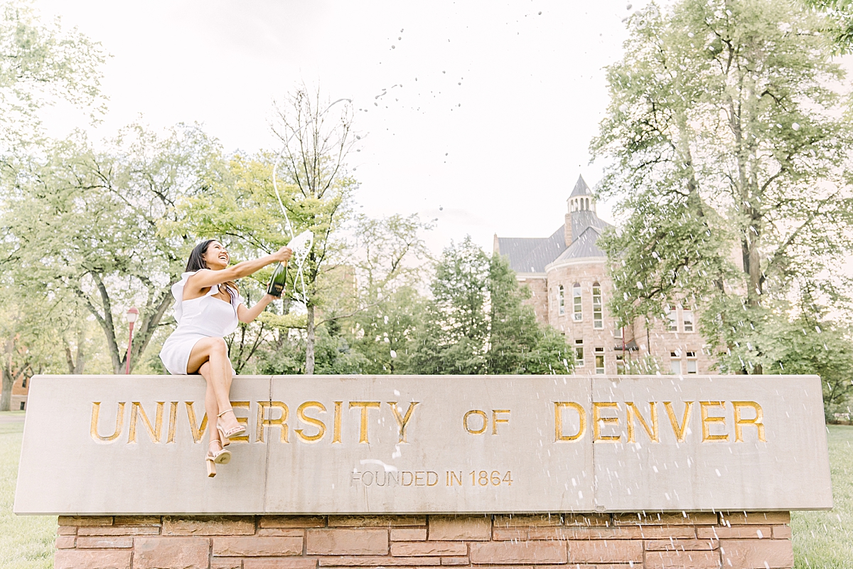 DU Grad does at a champagne pop at University of Denver sign.