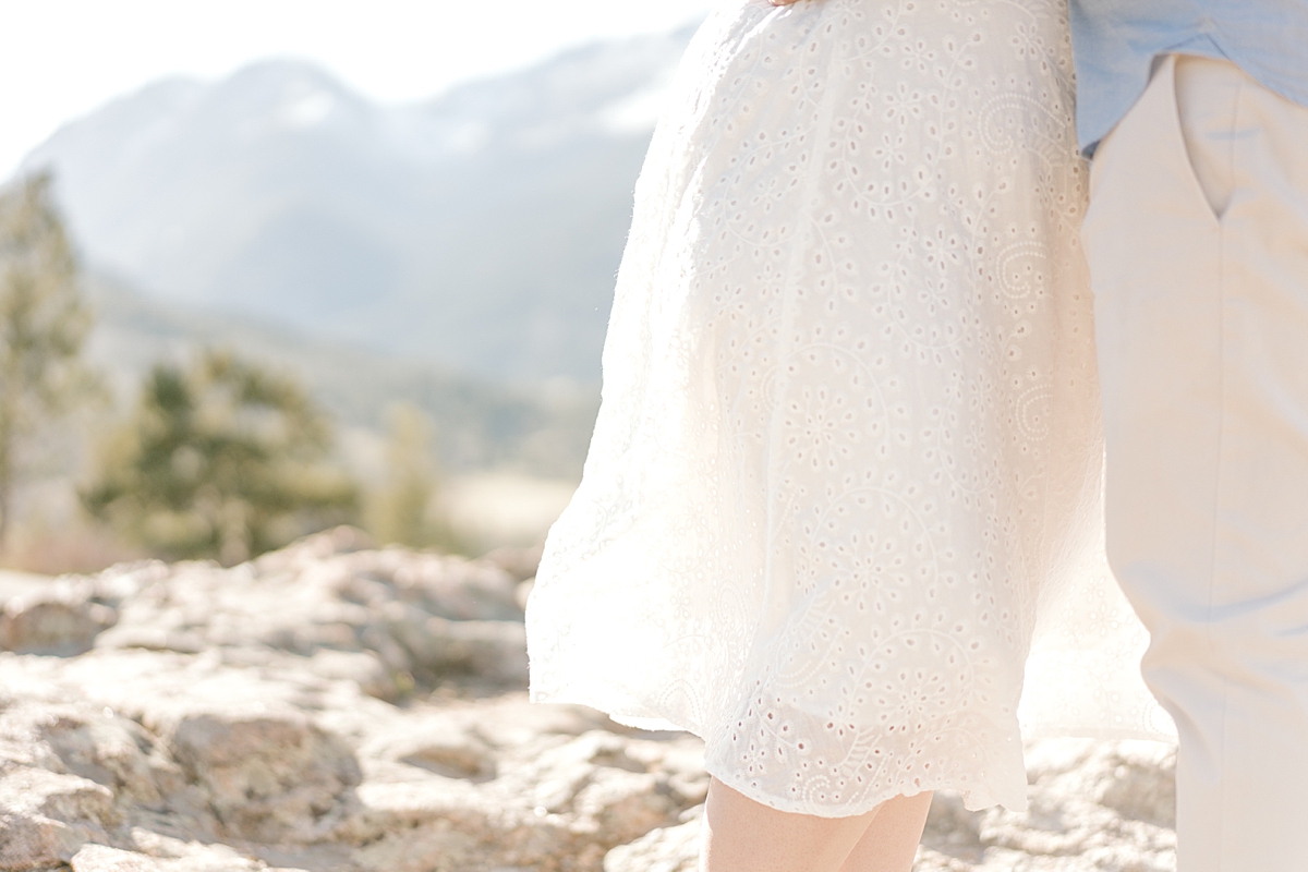 A woman wears an eyelet lace dress on rocks in the Colorado Rocky Mountains.