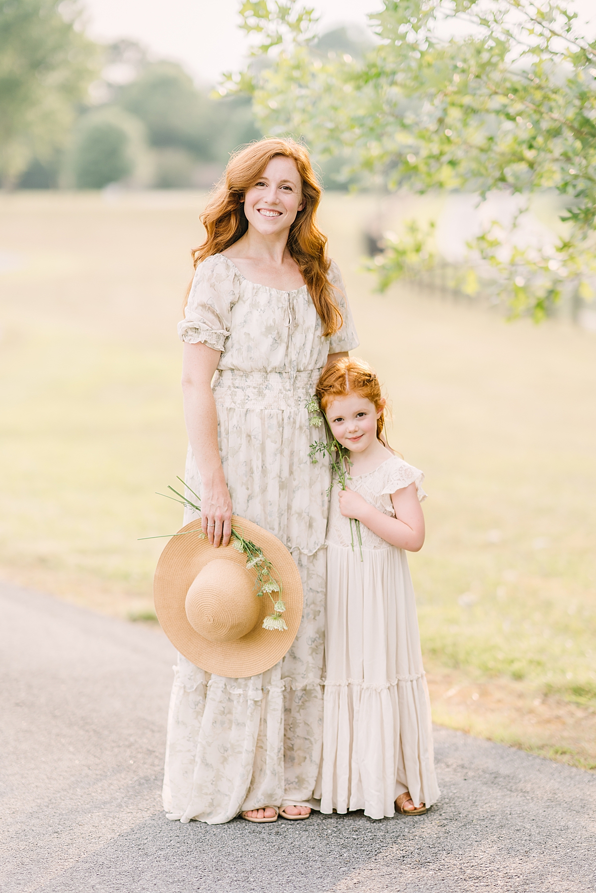 mom with red hair in flowy dress poses with cute daughter in flowy dress