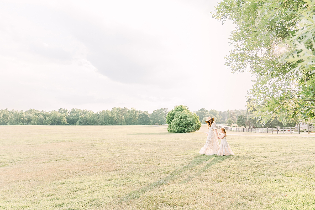 mom and daughter walk together in an open field in Georgia