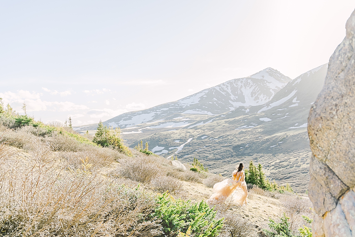 a girl in a fluffy peach tulle dress runs down the mountain at Guanella pass