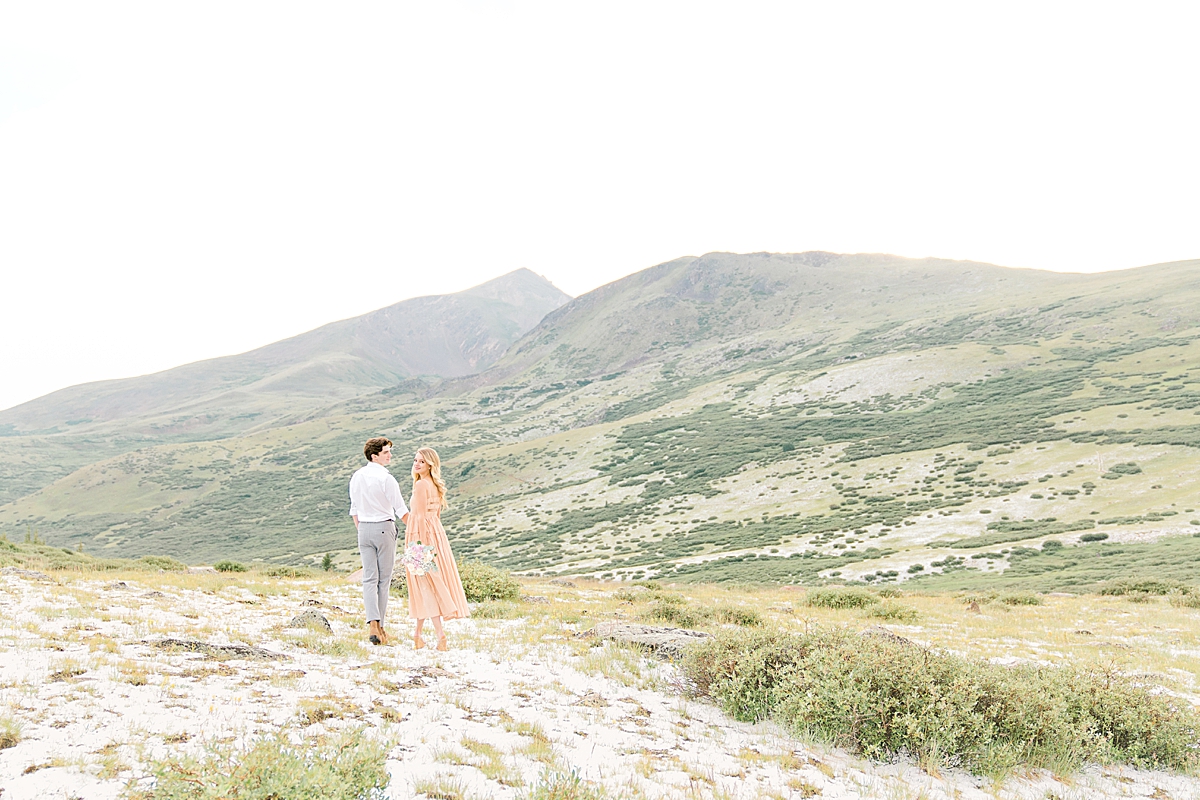 A couple walks on a hill at Guanella Pass for engagement photos.