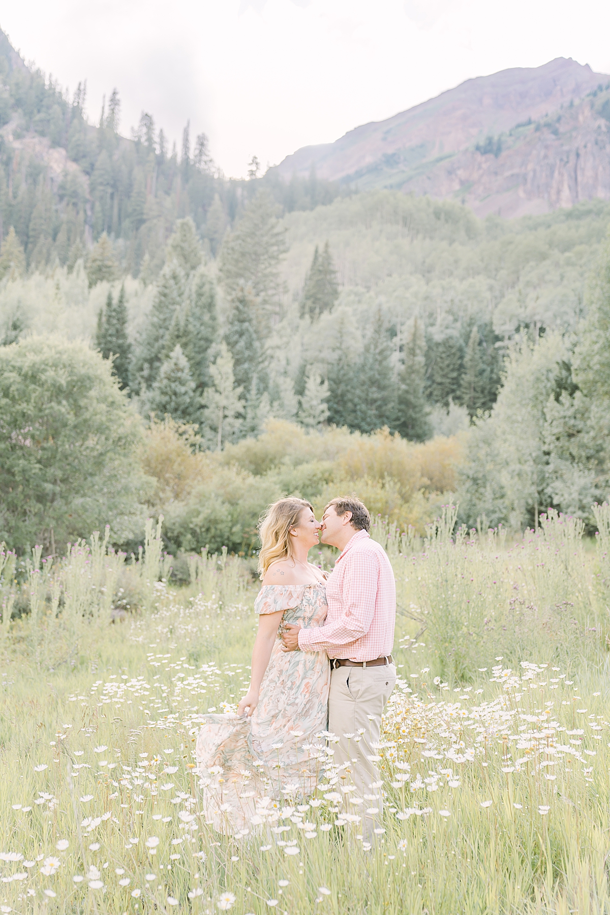 A couple kisses in the wild daisies in Aspen Colorado.