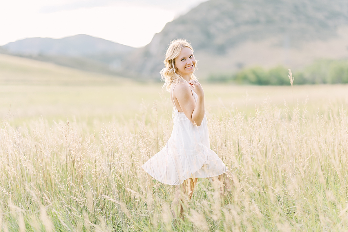 Pretty blonde senior girl frolics through a meadow.