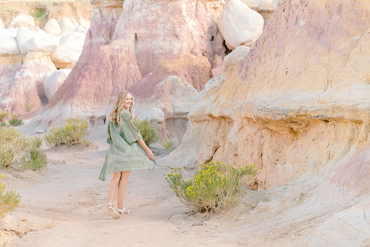 A girl in a green lace dress walks through the paint mines.