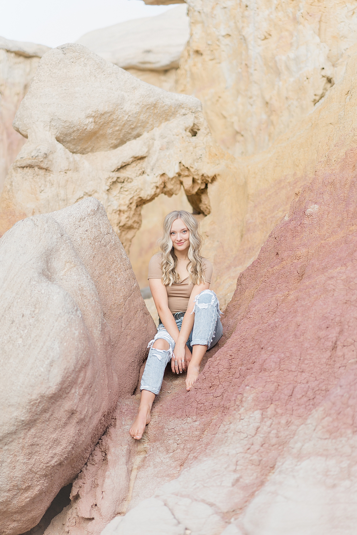 A graduating senior looks at the camera while sitting on the Paint Mines.