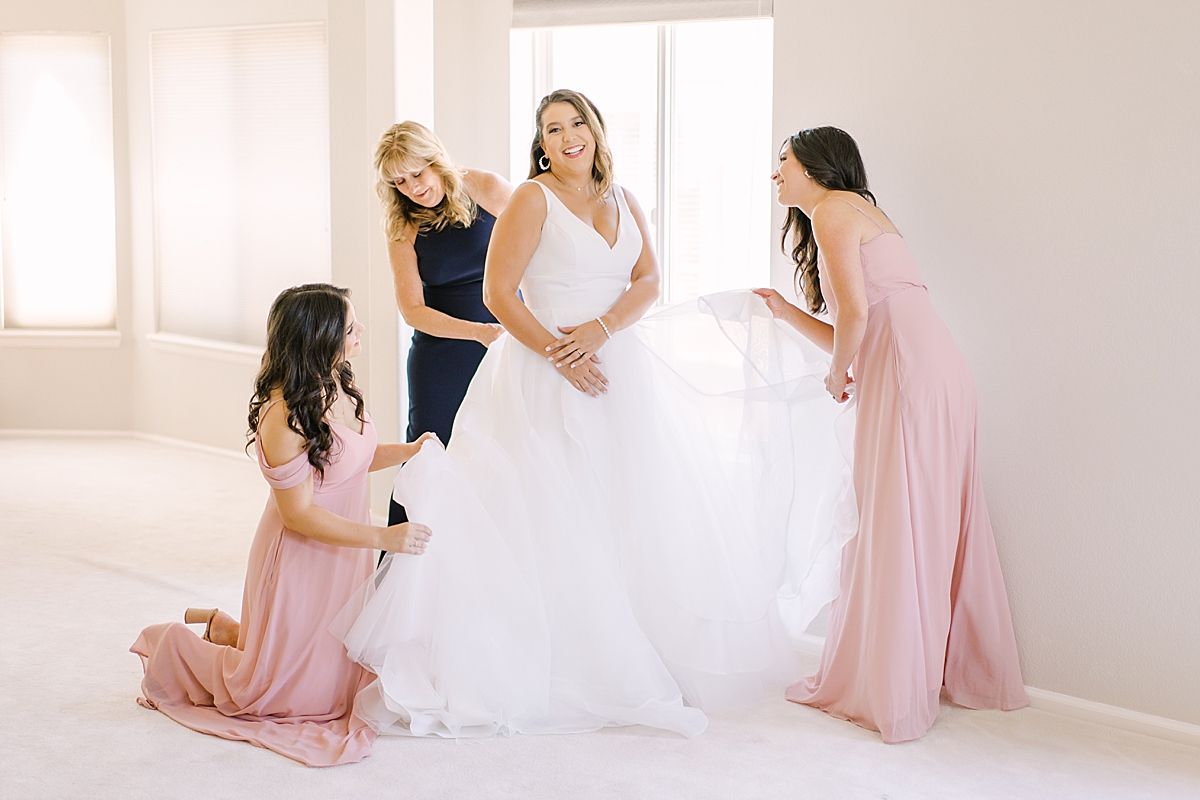 bridesmaids helping fluff bridal dress