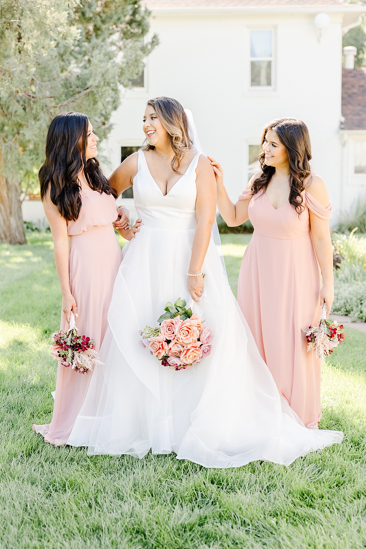 A bride laughs with her bridesmaids and sisters.