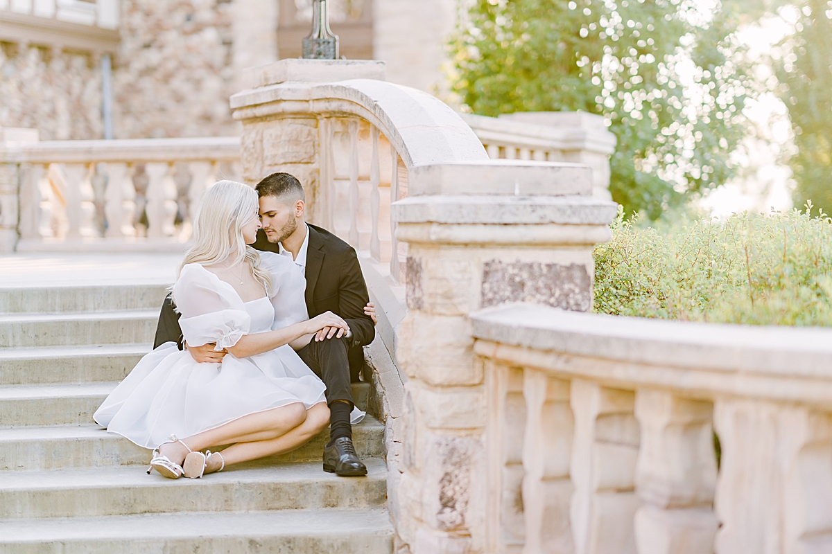 An engaged couple poses on the stairs of the Highlands Ranch Mansion.