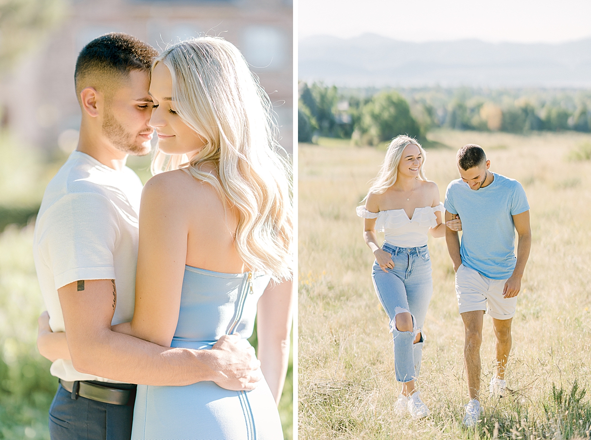 A sweet couple in blue and white walk through a field in front of the mountains.