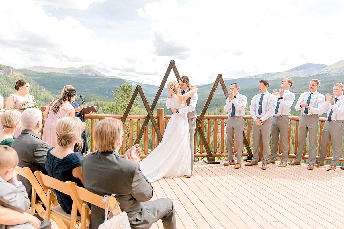 A bride and groom share their first kiss on the deck at The Lodge at Breckenridge.
