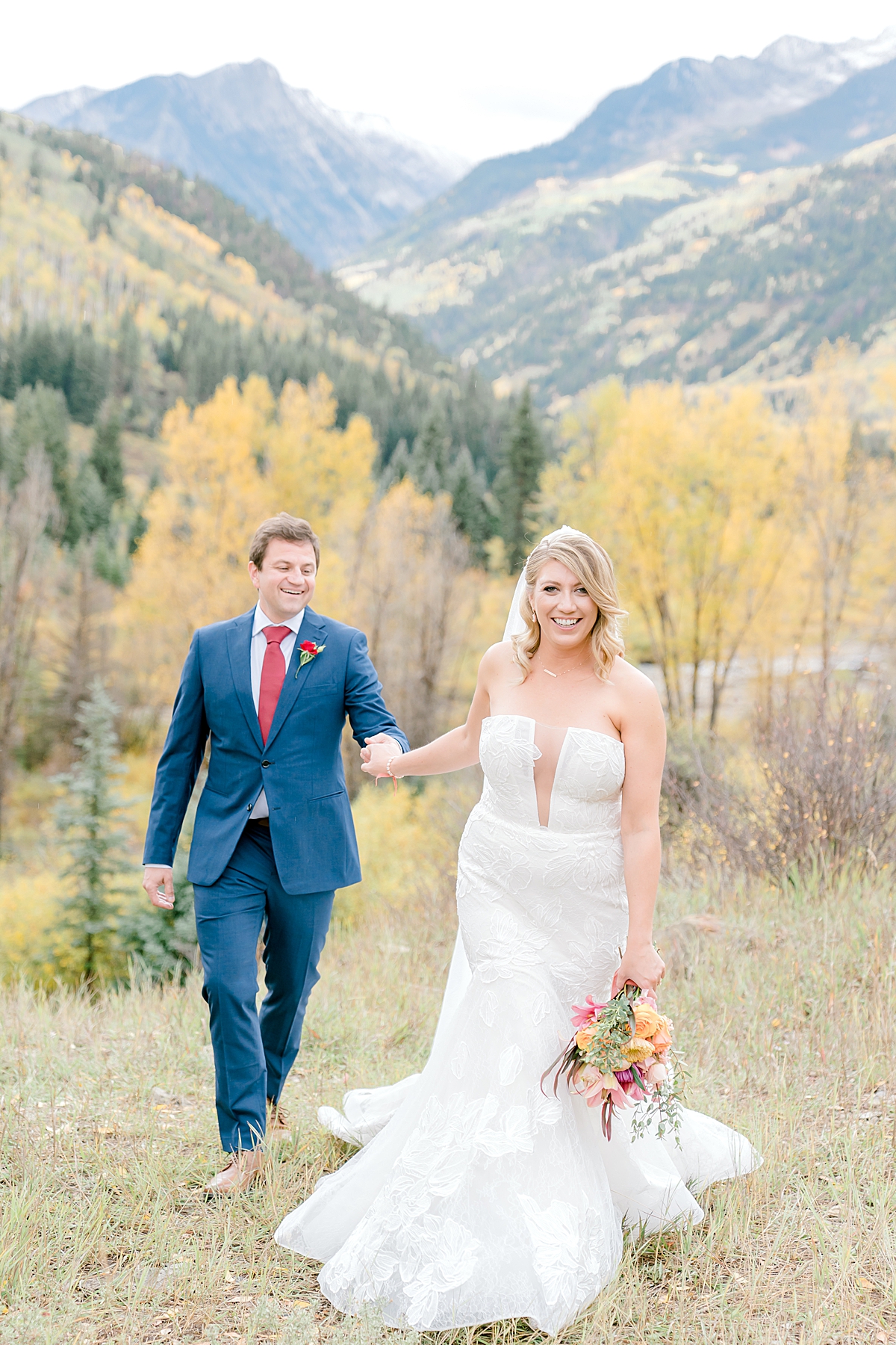 A bride and groom walk through the aspens near Chair Mountain Ranch.