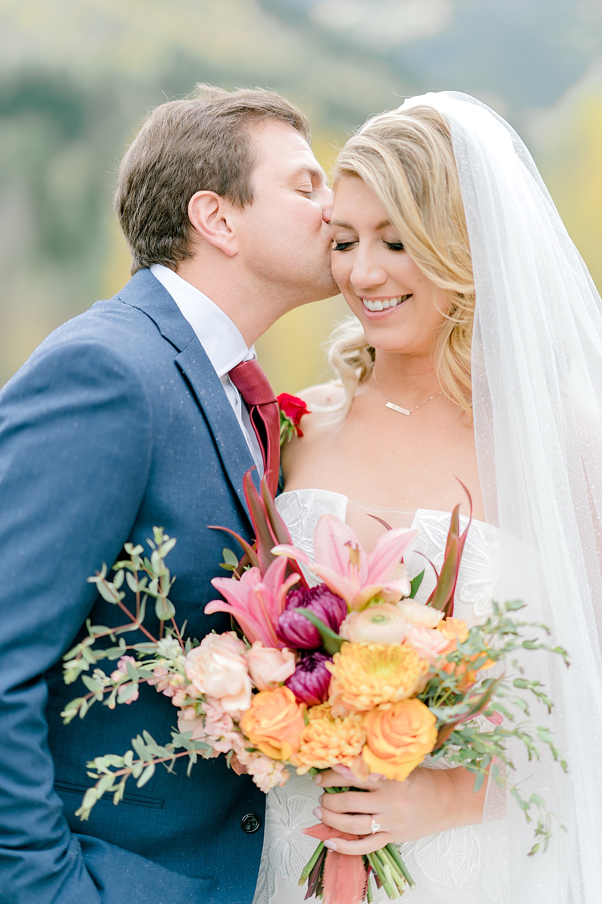 A groom sweetly kisses his bride's cheek at their Aspen Colorado fall wedding.