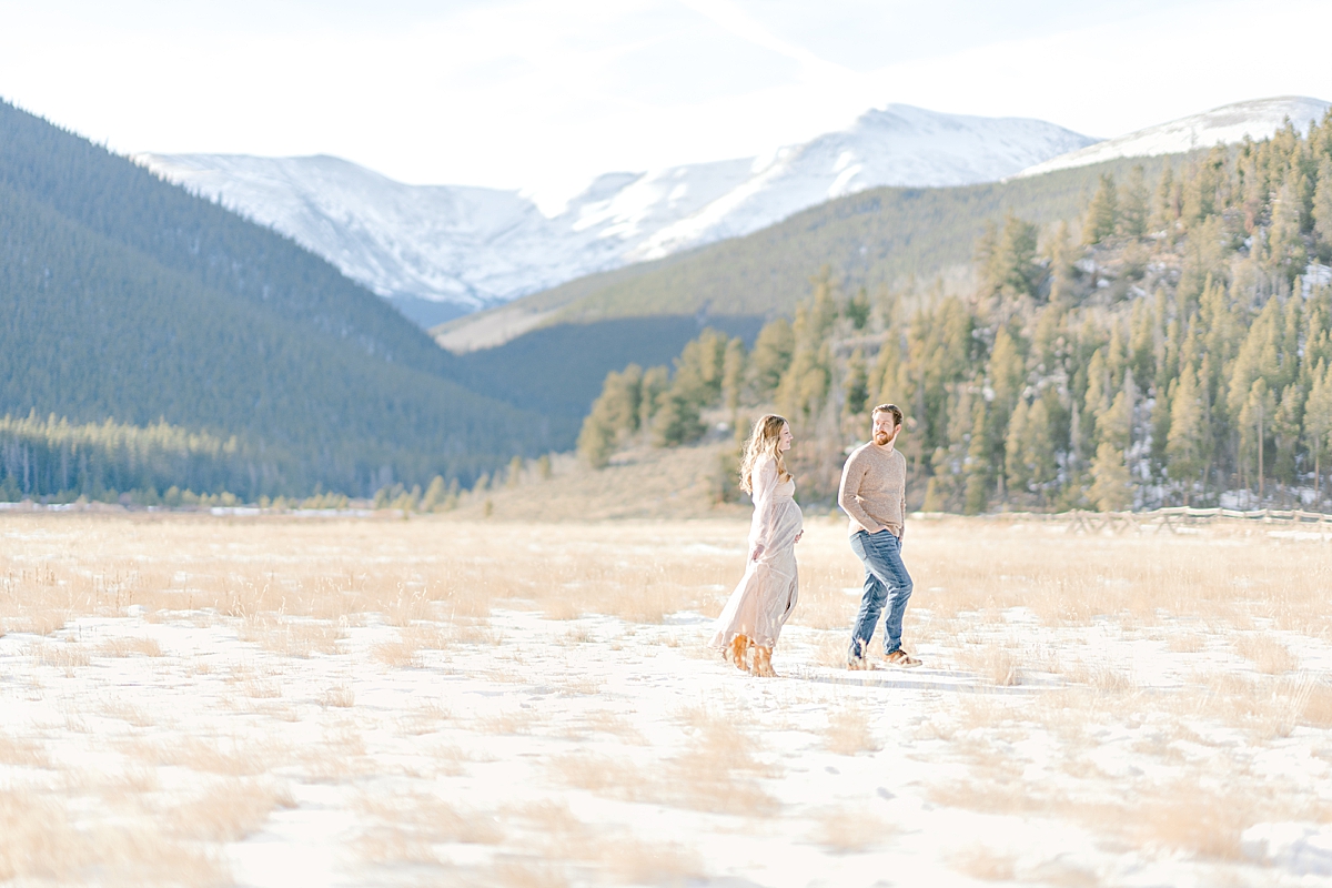 A couple awaiting their first baby walks in the meadow at Duck Creek Picnic area in the Rocky Mountains.