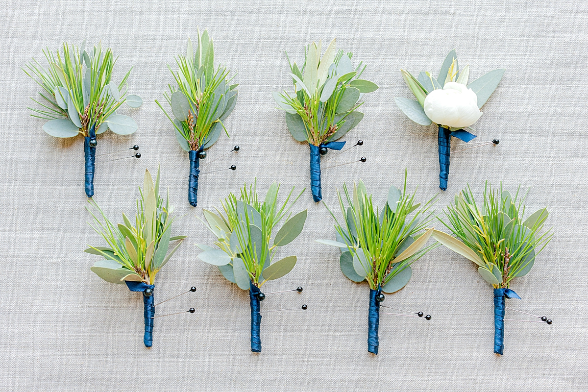 boutonnieres with pine needles and eucalyptus wrapped in blue ribbon