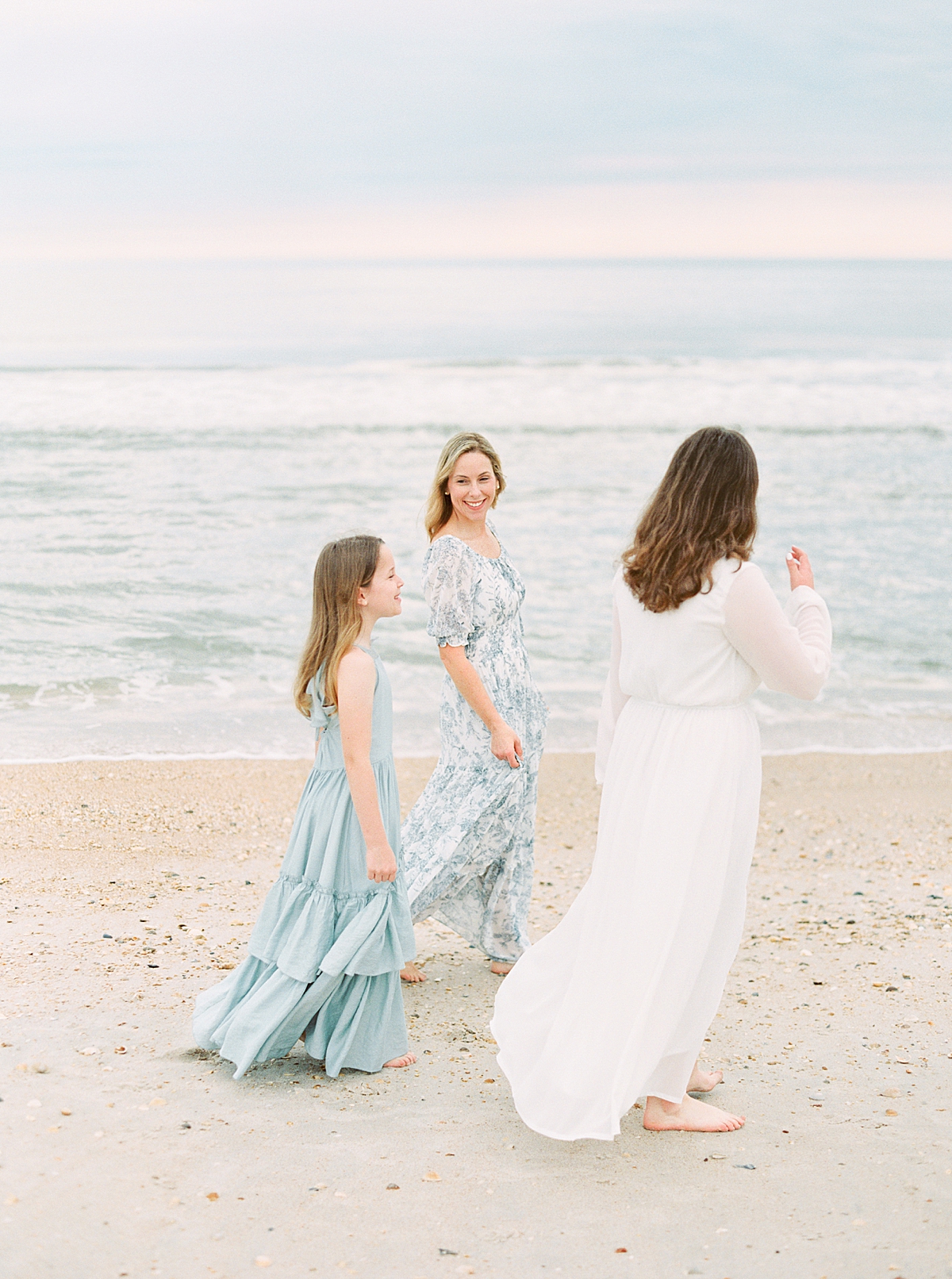 A Mom and her two daughters take beach family photos in Ponte Vedra, FL while wearing blue dresses.
