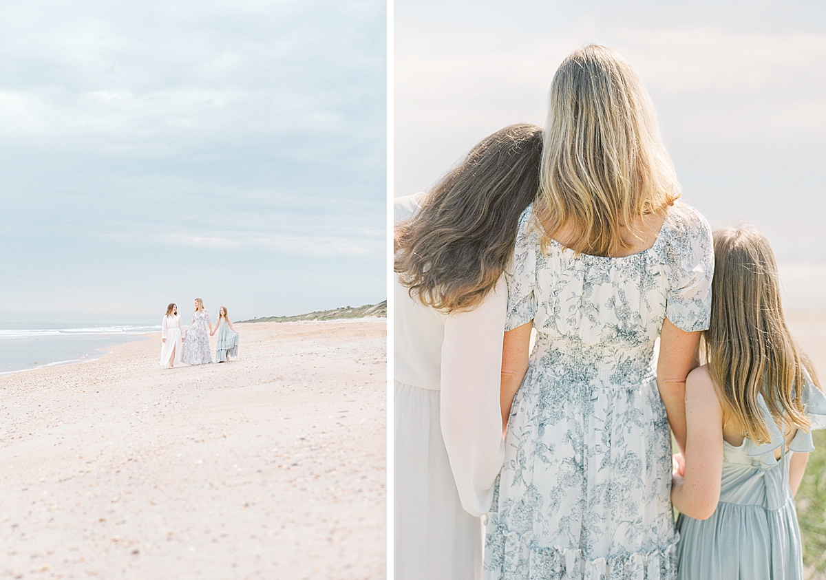 A family in pretty dresses hugs at the beach.