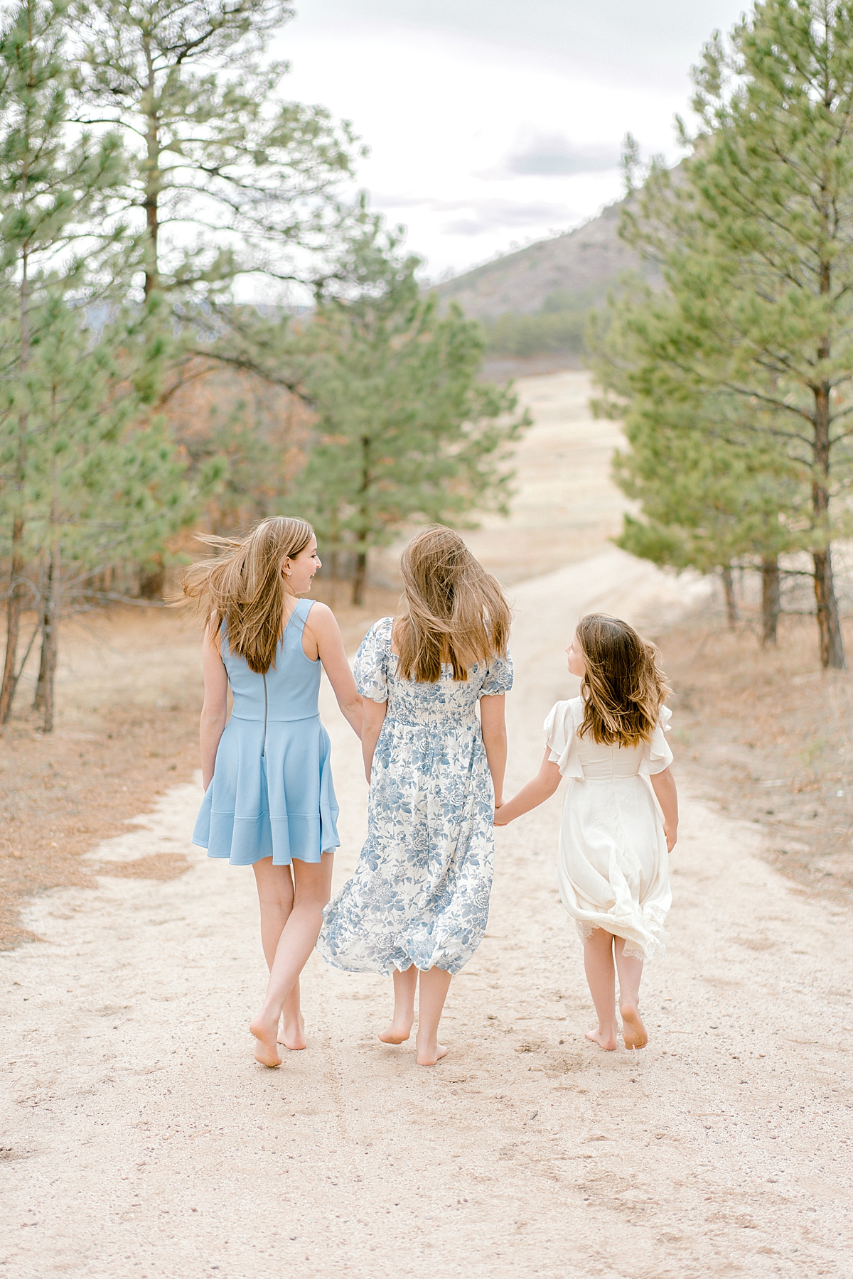 Three sisters walk hand-in-hand down a dirt path in Castle Rock.