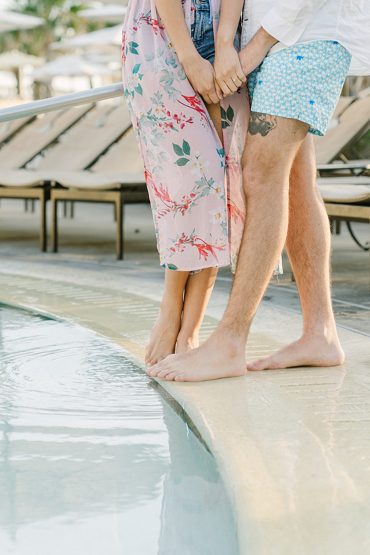 A couple dips their toes in the pool water.