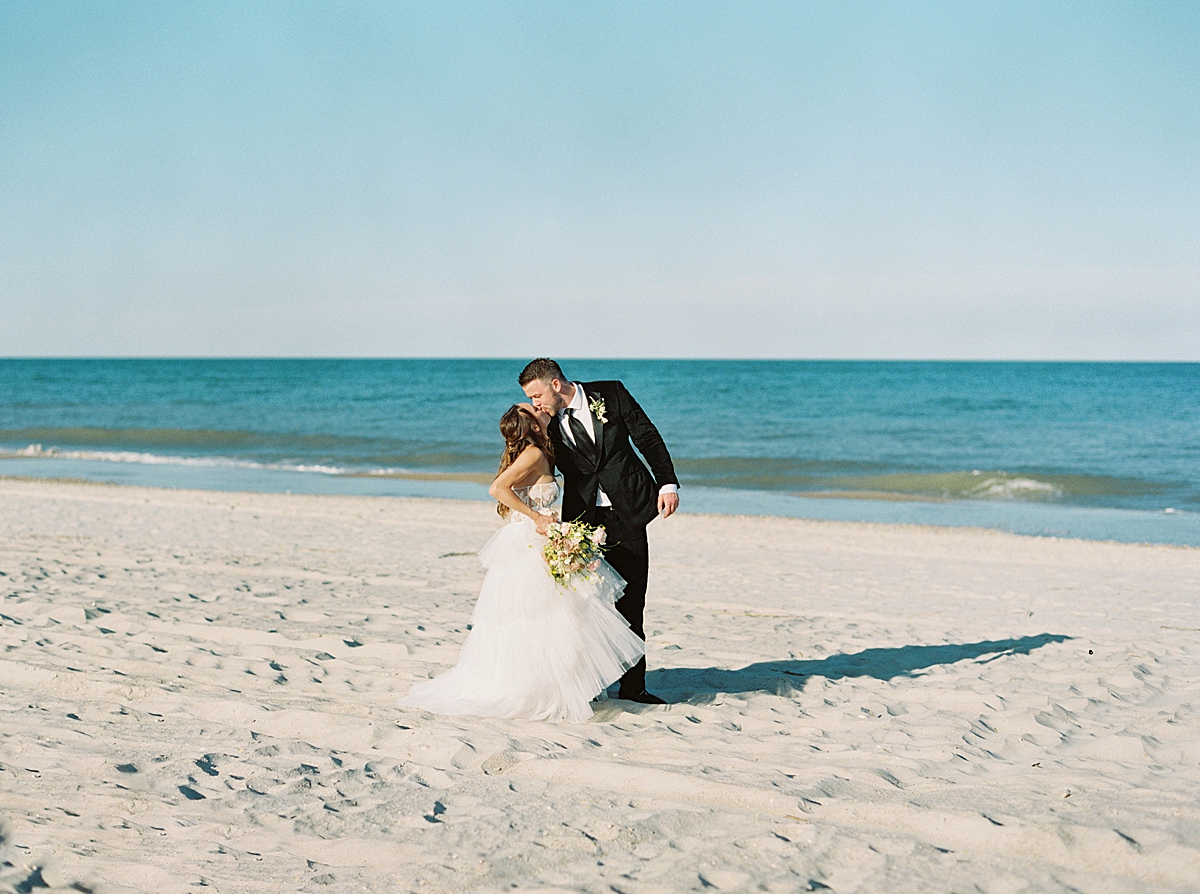 A just-married wedding couple kisses on the beach in Amelia Island, FL.