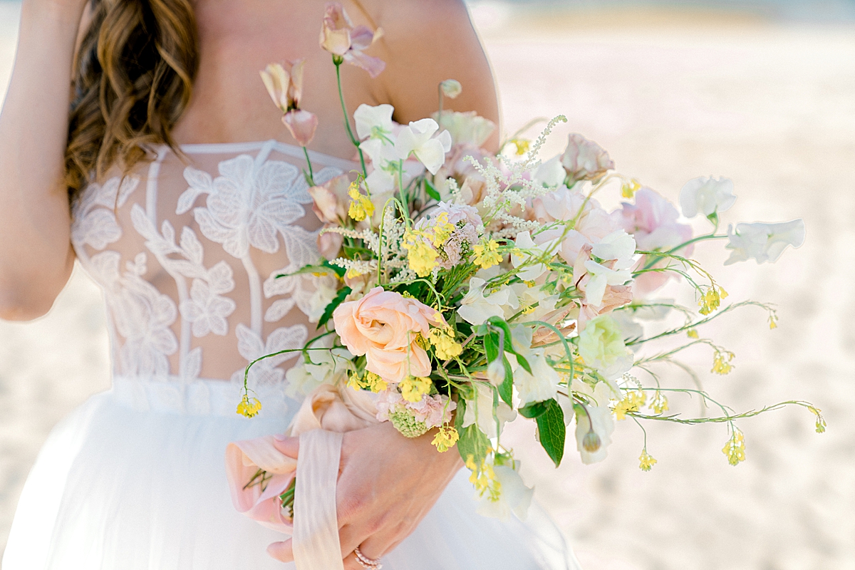 A pastel pretty wedding bouquet with sweet peas on the beach in Florida.