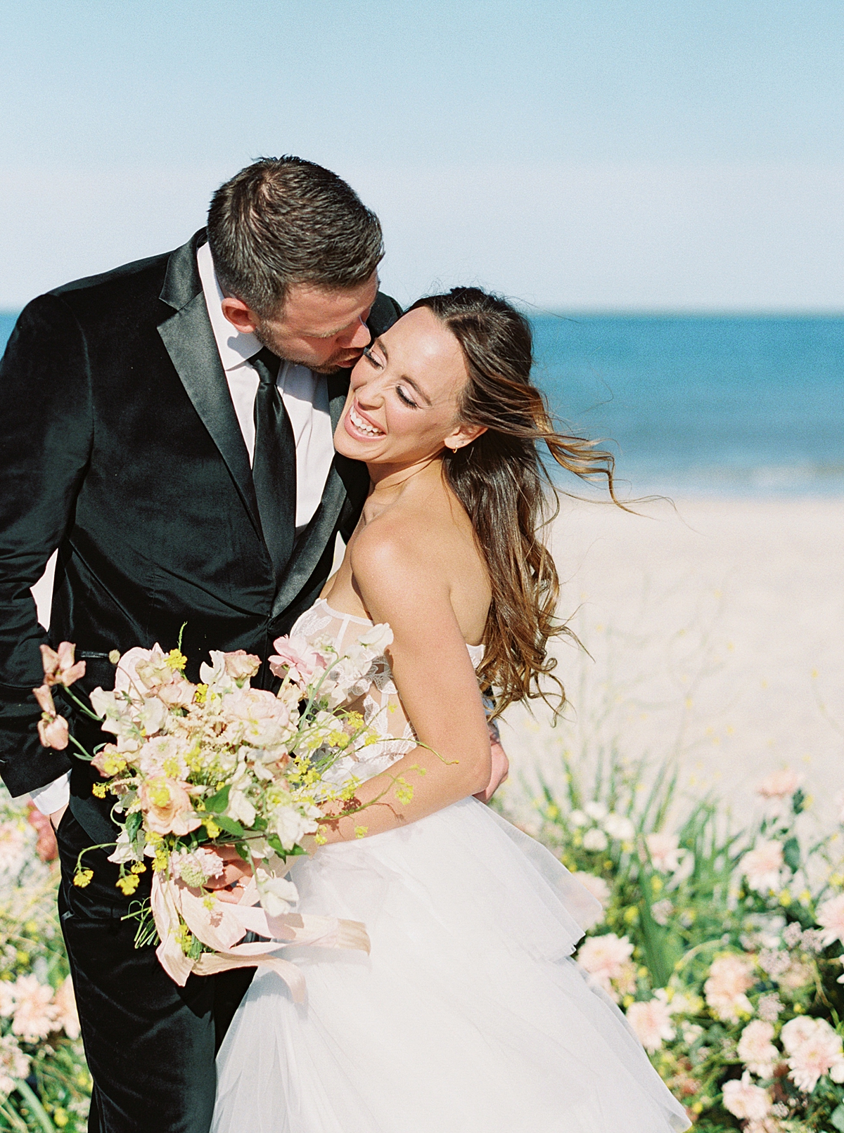 A groom kisses his bride on the beach at their Florida destination wedding.