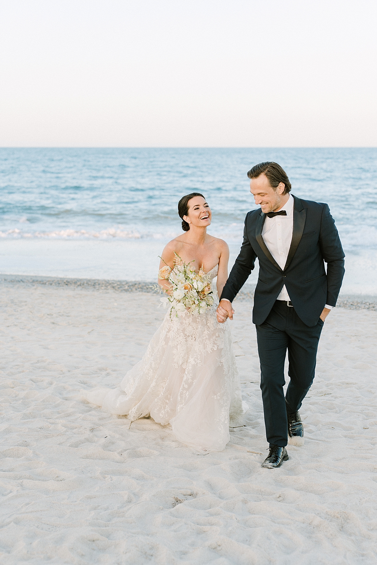 A bride and groom frolic on the beach during their luxury beach wedding on film.