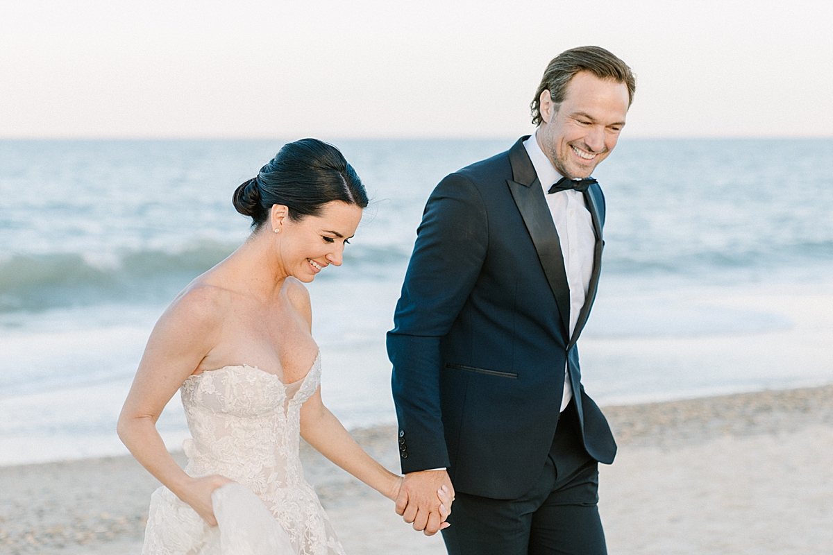 A bride and groom walks along the beach at their luxury beach wedding on film