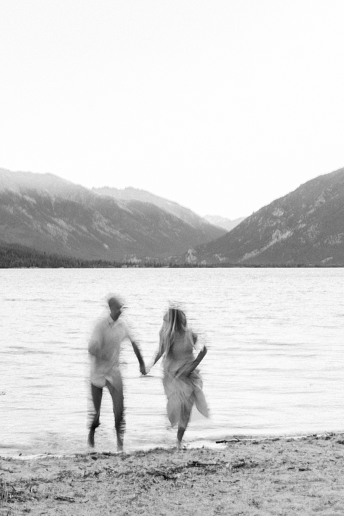 A blurry black and white photo of a guy and girl running out of a lake
