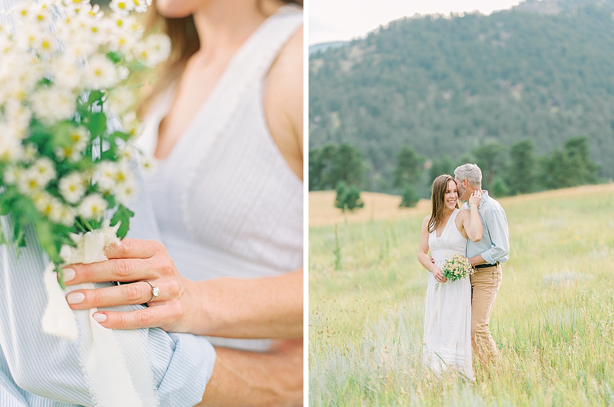 A man holds his fiancé in a field under the mountains in Boulder.