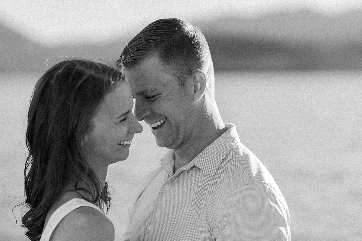 An engaged couple laughs at giggles together near Sapphire Point in a grainy black and white photo.
