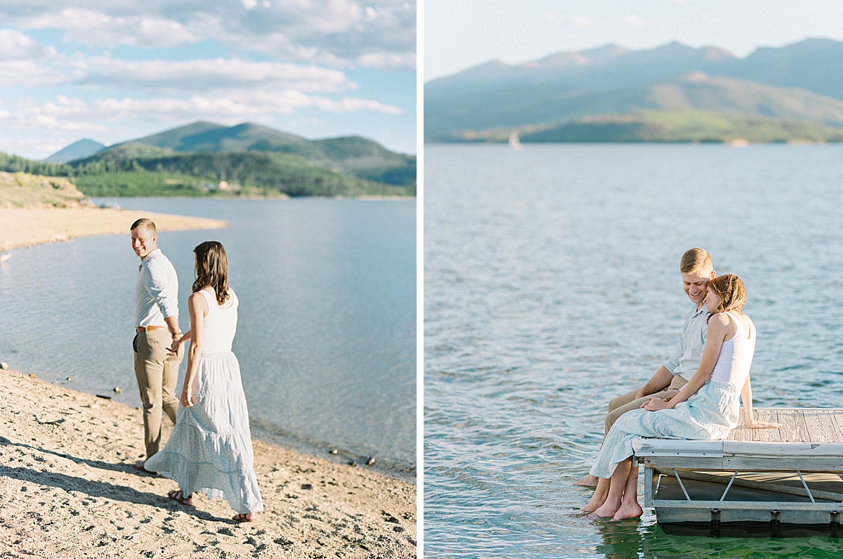 An engaged guy and girl sit at the edge of a dock on Lake Dillon, holding hands and nuzzling together.