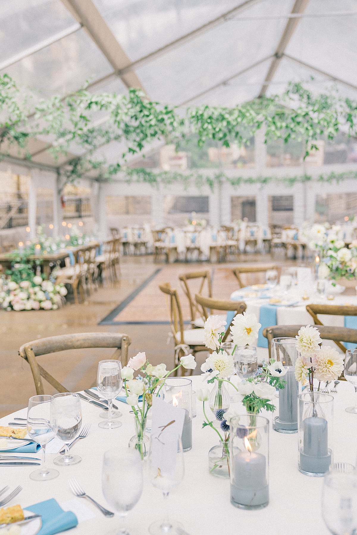 A dusty blue wedding reception with draping ruscus greenery in the Vail Arrabelle Square, designed by Kira Events.