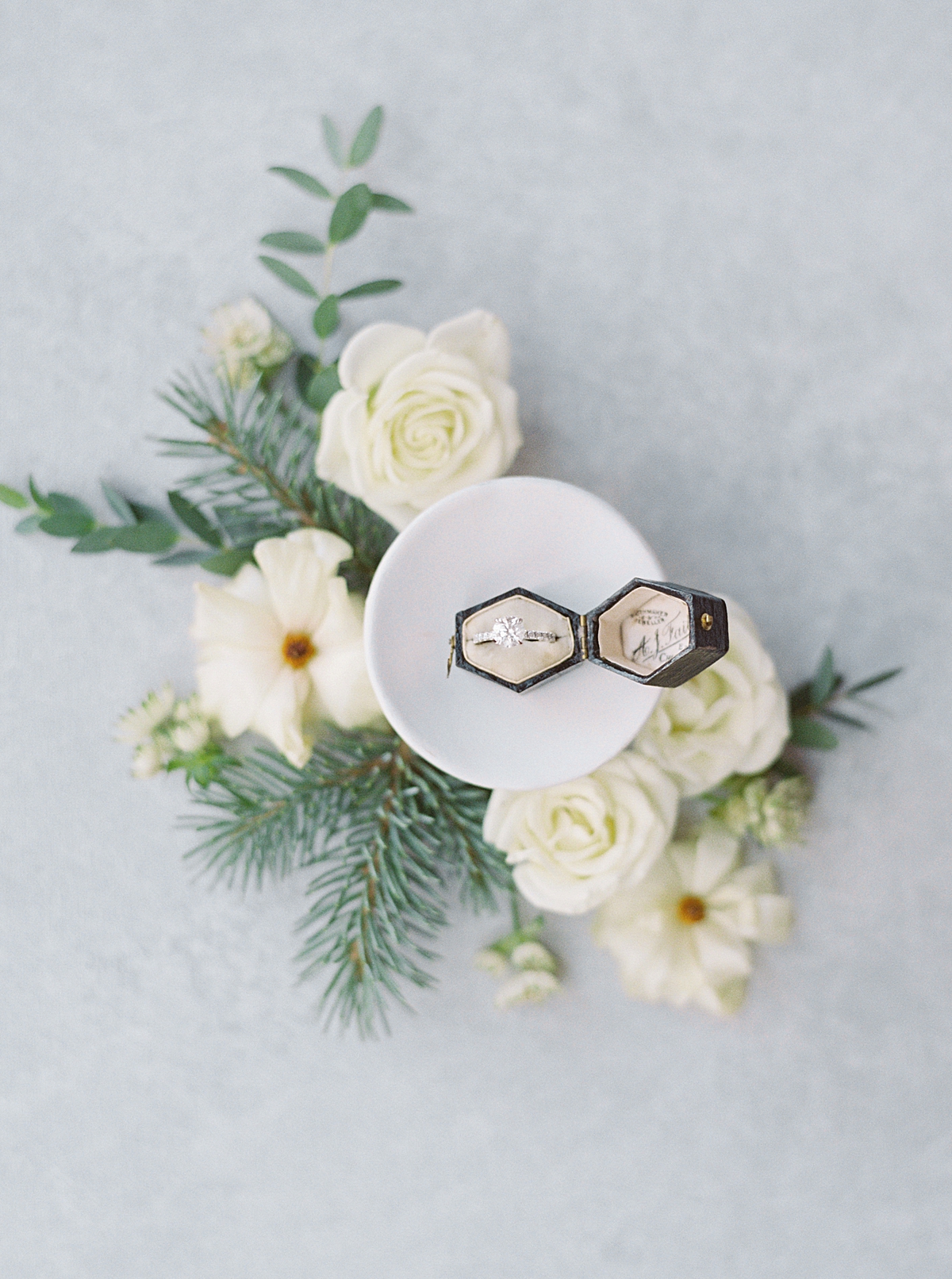 a flat lay with antique ring box, white roses, and butterfly ranunculus