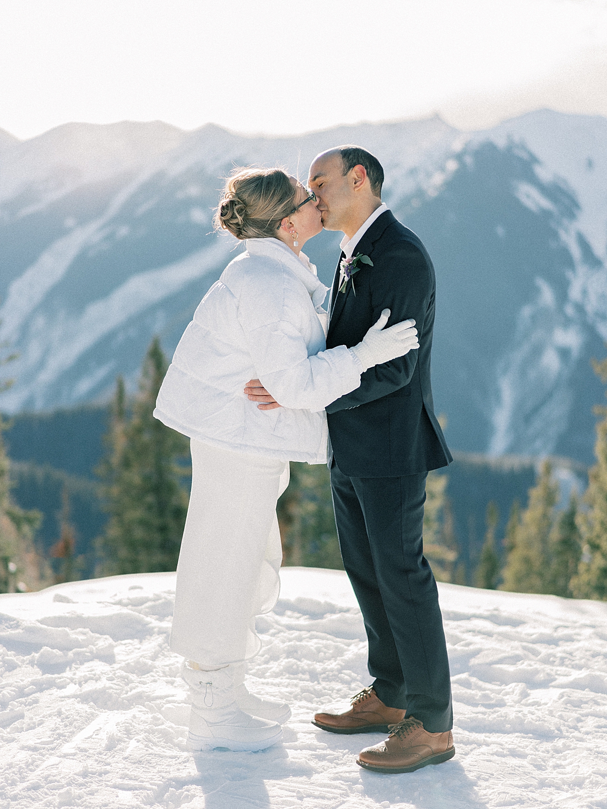A bride and groom share their firsts kiss after reading vows to each other, on the snowy mountain in Aspen.