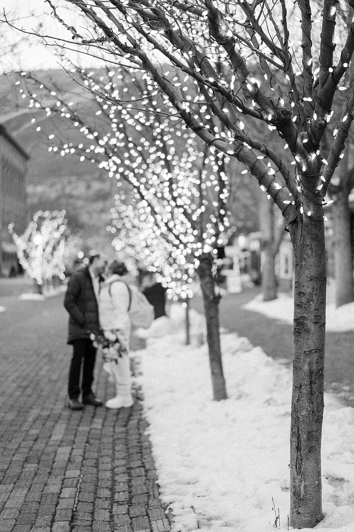 A bride and groom kiss under the sparkling lights in downtown Aspen in December.