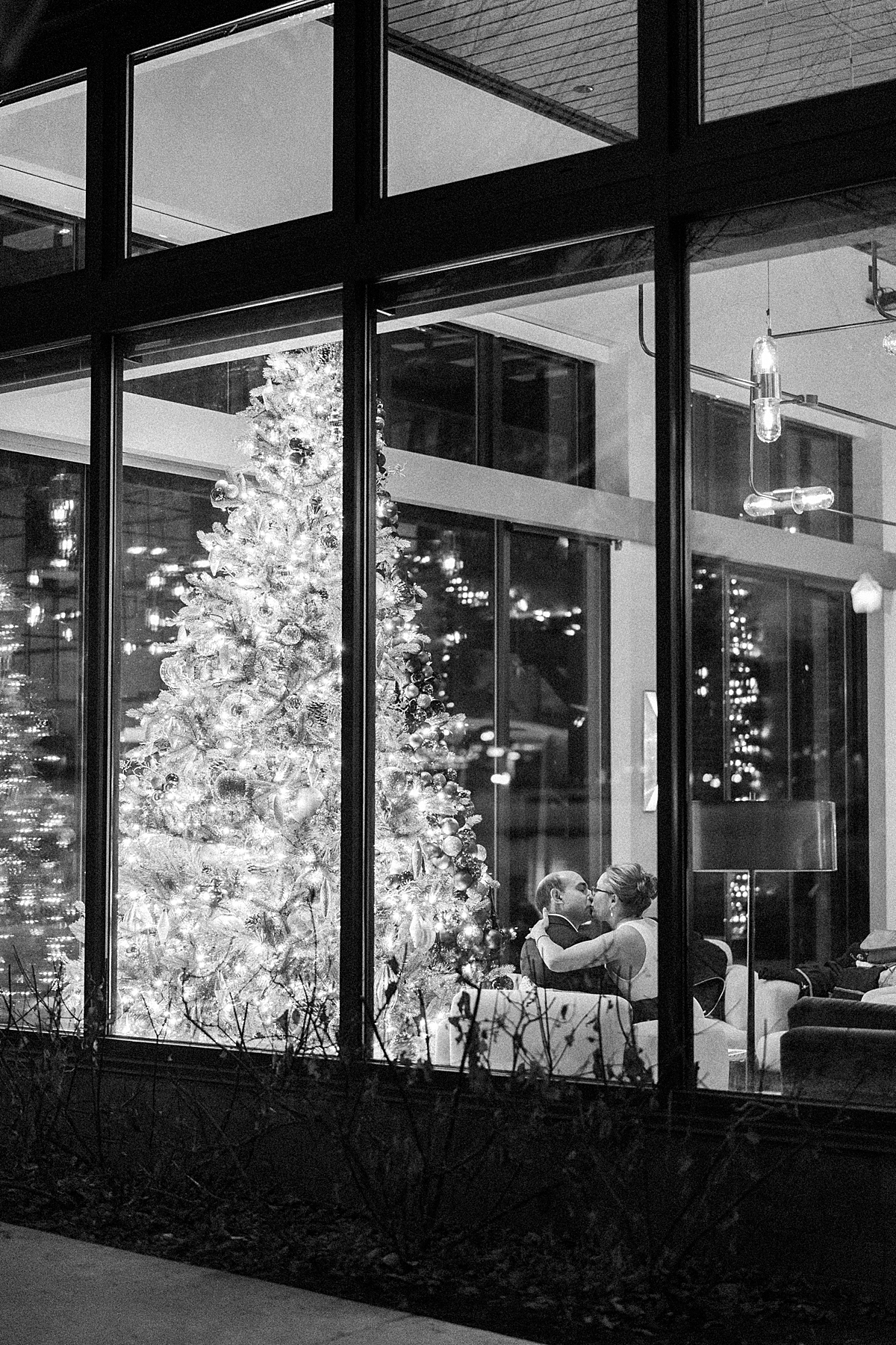 A newly eloped couple kiss by the Christmas tree at Limelight hotel in downtown Aspen, as capture on camera from outside the hotel.
