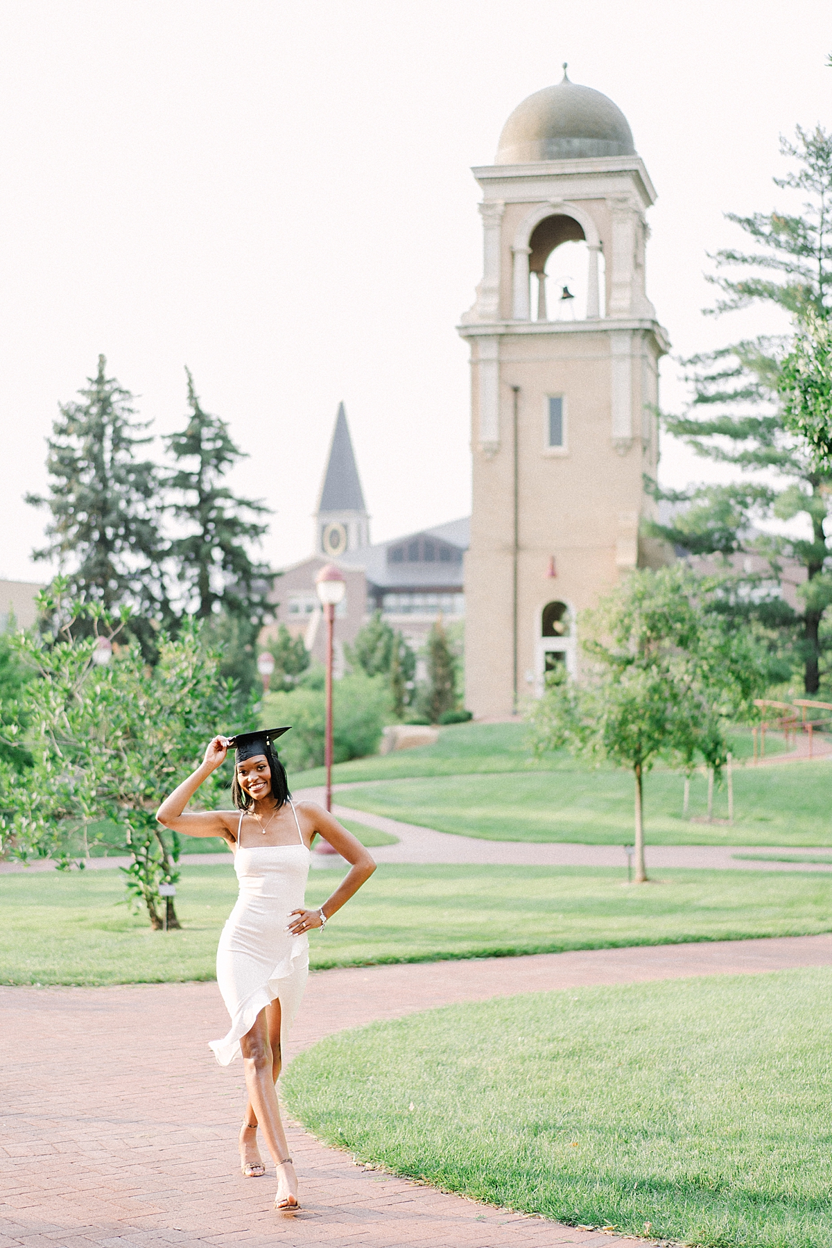 denver graduate walking near the buchtel tower, while taking her University of Denver graduation photos