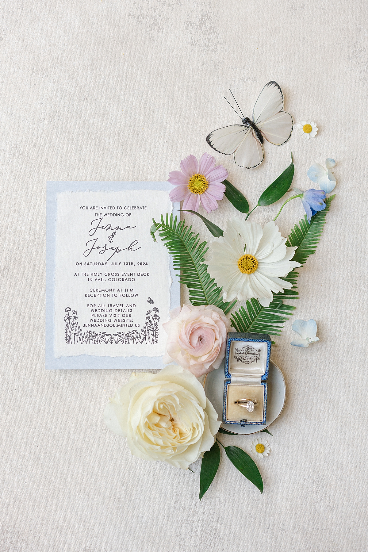 A beautiful wedding invitation for a Vail wedding is surrounded by pastel wildflowers.