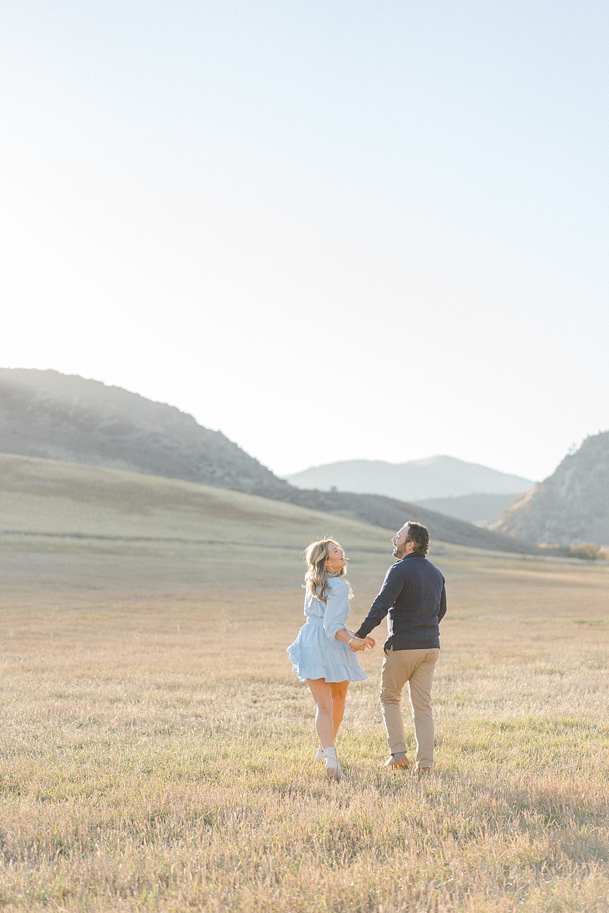 A couple playfully walks by a mountain.