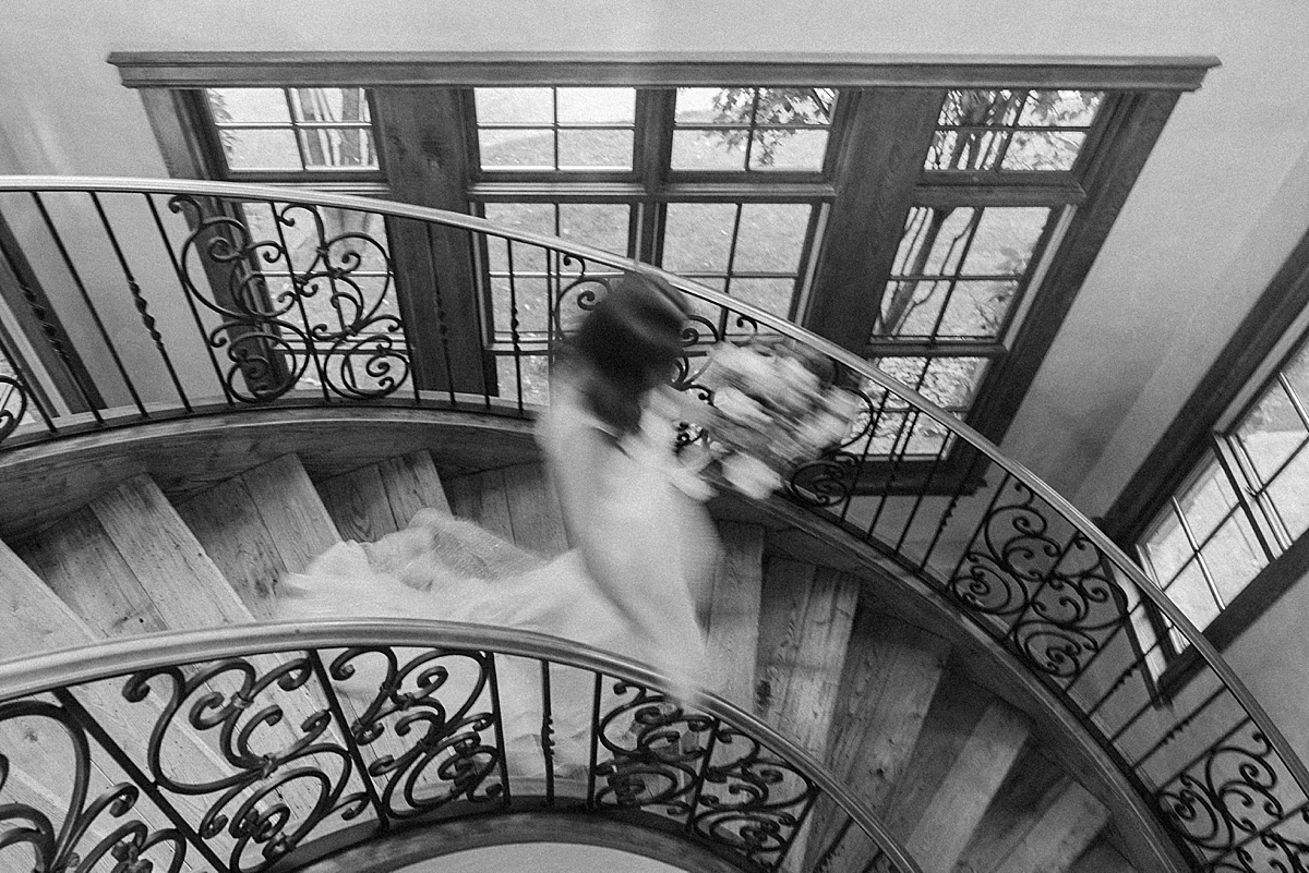 Black and white motion blur photo of a bride walking down a staircase