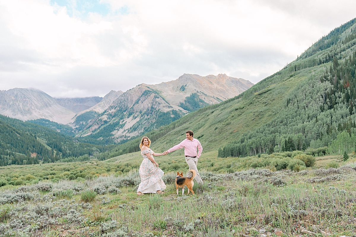 A couple walks through the mountains with their dogs for Aspen Colorado engagement photos.