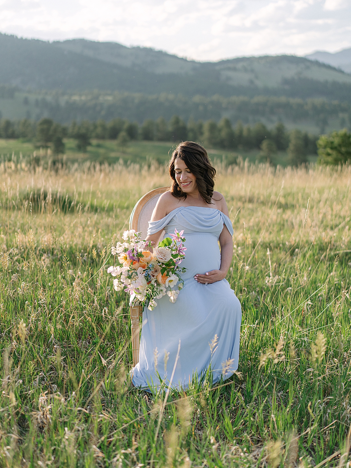 expecting mother in blue dress and floral bouquet for Colorado maternity session