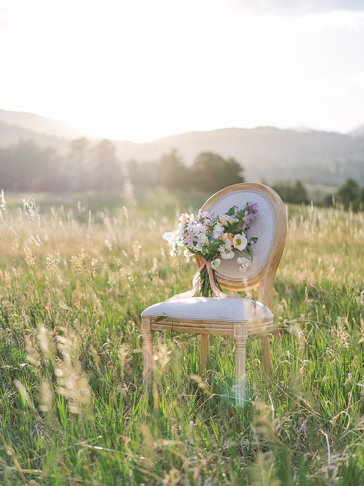 a floral bouquet sits on a French-style chair in the Colorado foothills at sunset